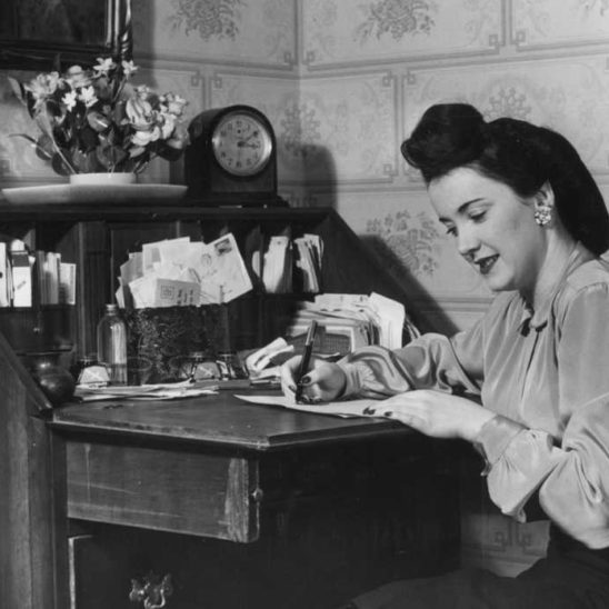 circa 1945:  A woman sits at a fold-out desk and writing a letter.  (Photo by Lambert/Getty Images)